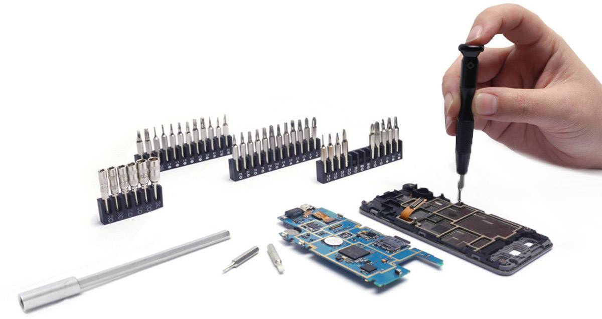 Hand montiert elektronische Bauteile mit einem Schraubenzieher auf einer Leiterplatte, umgeben von verschiedenen Werkzeugen und Bits.