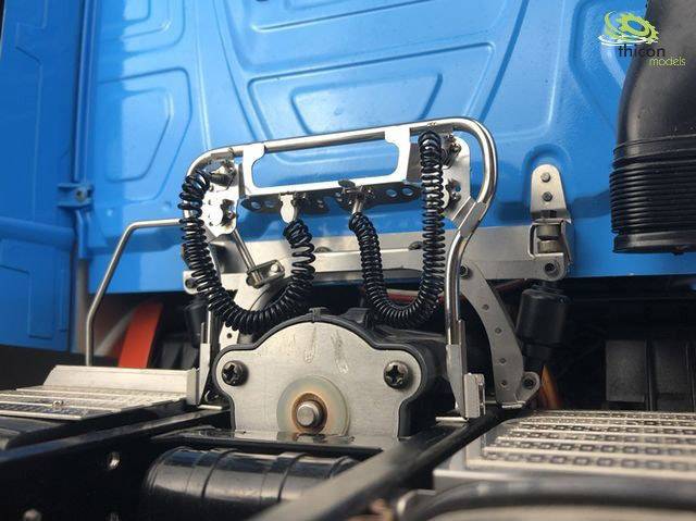 Nahaufnahme eines LKW-Modells mit blauer Kabine und detailliertem Aufliegeranschluss, Spiralkabeln und Metallkomponenten.