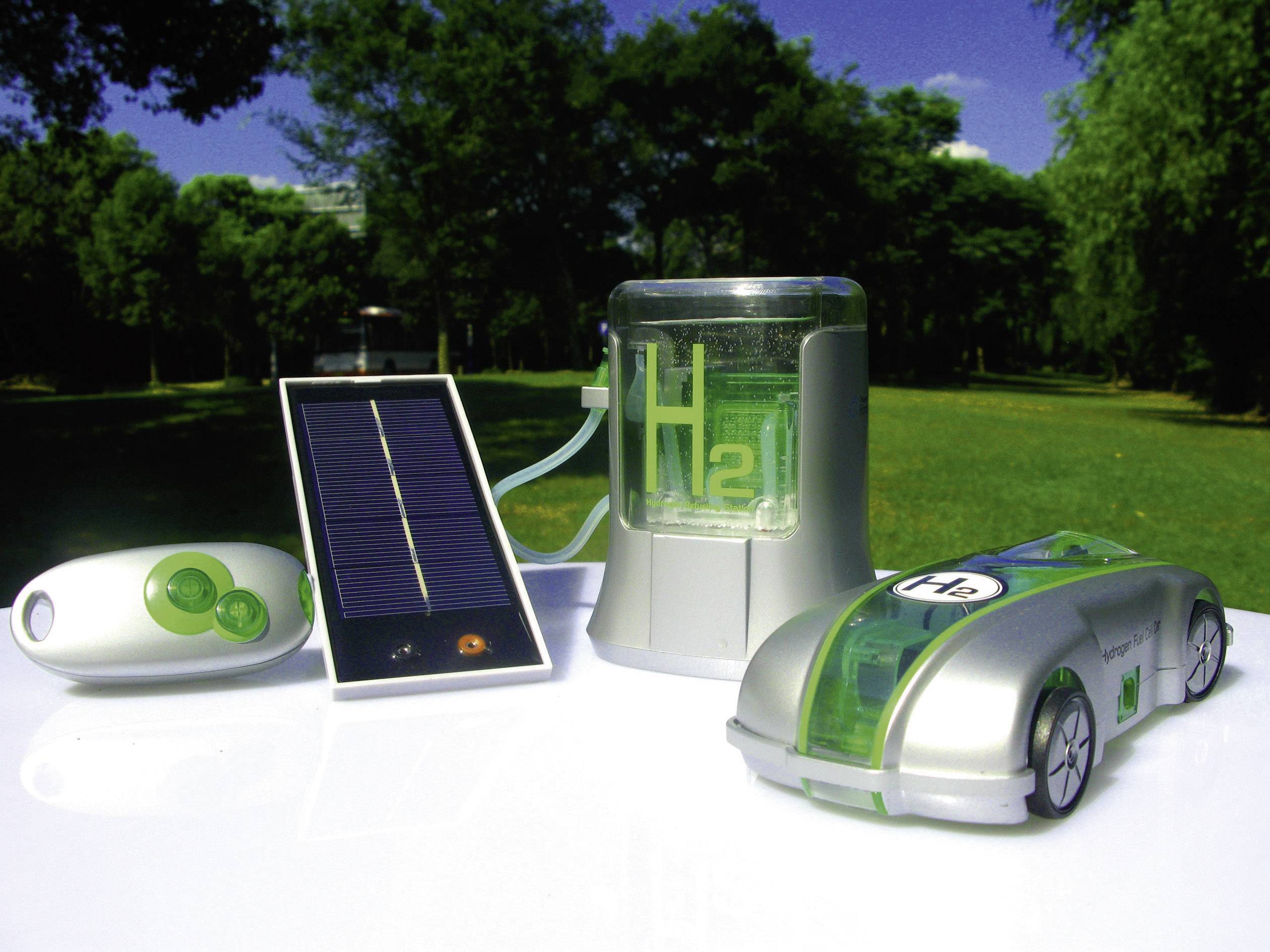 Wasserstoffauto-Modell mit Solarzellen und Energiespeicher, dargestellt auf einem Tisch in einem grünen Park unter blauem Himmel.