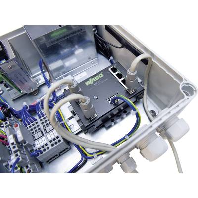 Ein offenes Elektronikgehäuse mit einem Netzwerk-Switch der Marke WAGO, verbunden durch Kabel. Verschiedene Anschlüsse sichtbar.