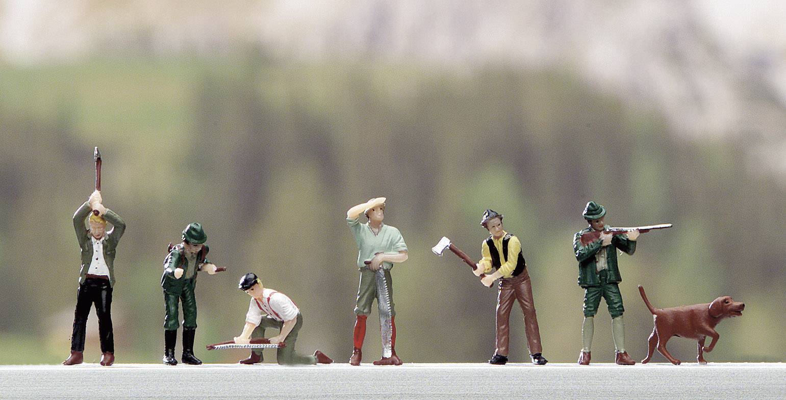 Sechs Miniaturfiguren von Förstern in unterschiedlichen Posen mit Werkzeugen aufgestellt. Hund daneben. Hintergrund unscharf.