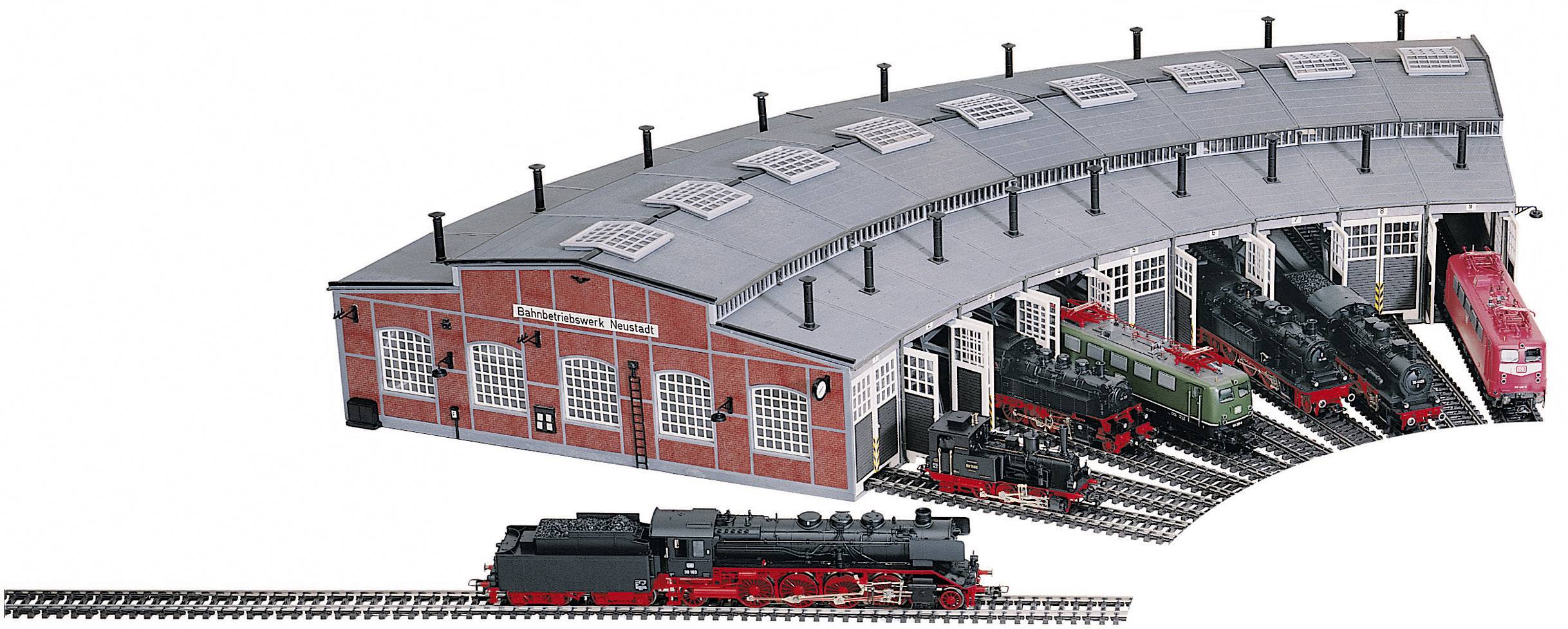 Ein halbkreisförmiges Eisenbahndepot mit sechs offenen Toren zeigt verschiedene Lokomotiven. Eine Lokomotive fährt auf den Gleisen.