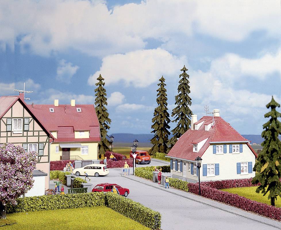 Eine malerische Wohngegend mit blauem Himmel, Fachwerkhäusern, einem roten Auto und Bäumen entlang der Straße.