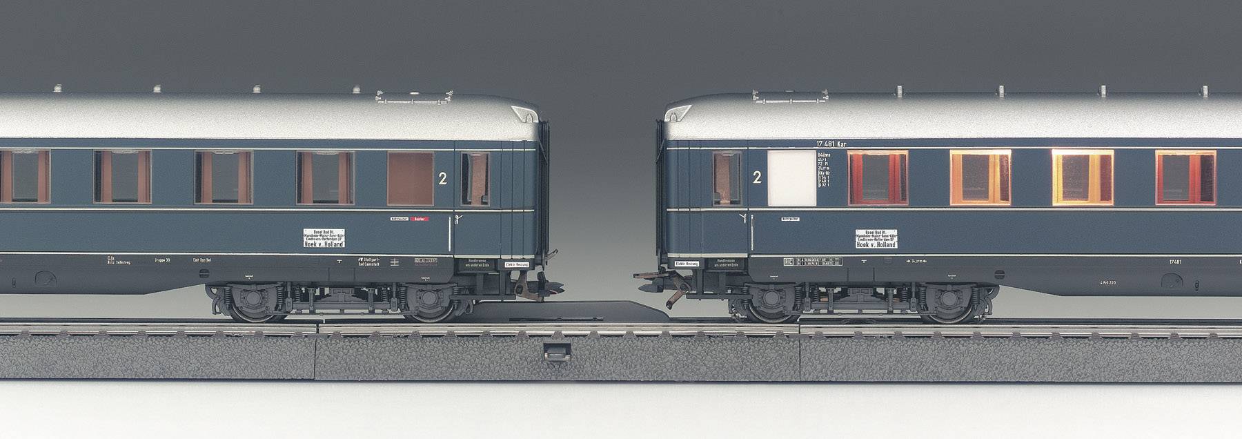 Zwei dunkelblaue Zugwaggons auf einem Gleis, links und rechts im Bild, mit Aufschriften '2' und 'Pullman'.