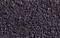 Nahaufnahme einer Textur aus vielen kleinen, dunklen Steinen oder Körnern, die eng aneinanderliegen und eine ungleichmäßige Oberfläche bilden.
