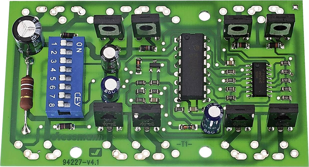 Eine grüne Leiterplatte mit verschiedenen elektronischen Komponenten wie Widerständen, Kondensatoren und einem DIP-Schalter.