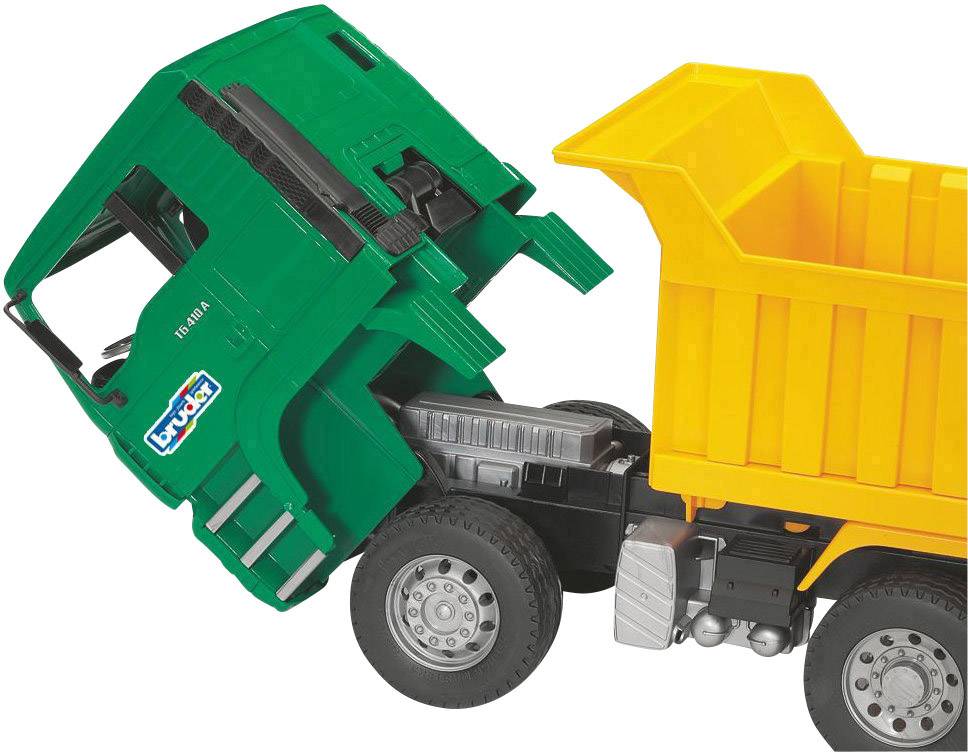 Ein Spielzeug-Lkw mit grünem Führerhaus und orangefarbenem Kipper steht schräg, als würde er etwas abladen.