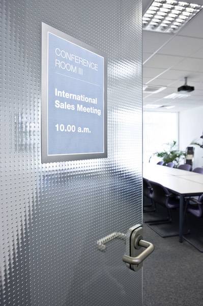 Der Konferenzraum III ist für ein internationales Verkaufstreffen um 10:00 Uhr vorbereitet. Ein Schild an der Tür gibt diese Information an.