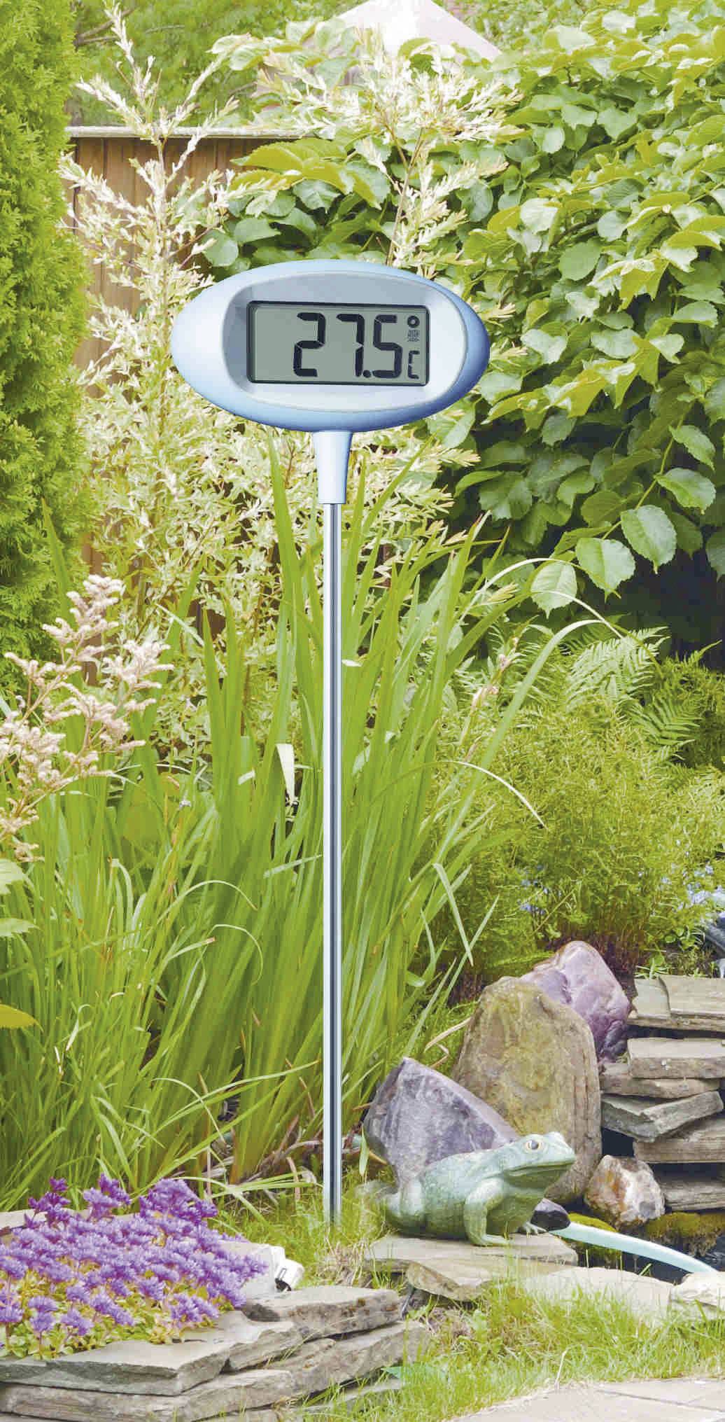 Garten-Thermometer zeigt 27,5 Grad Celsius an, aufgestellt zwischen Pflanzen und Steinen im Garten.
