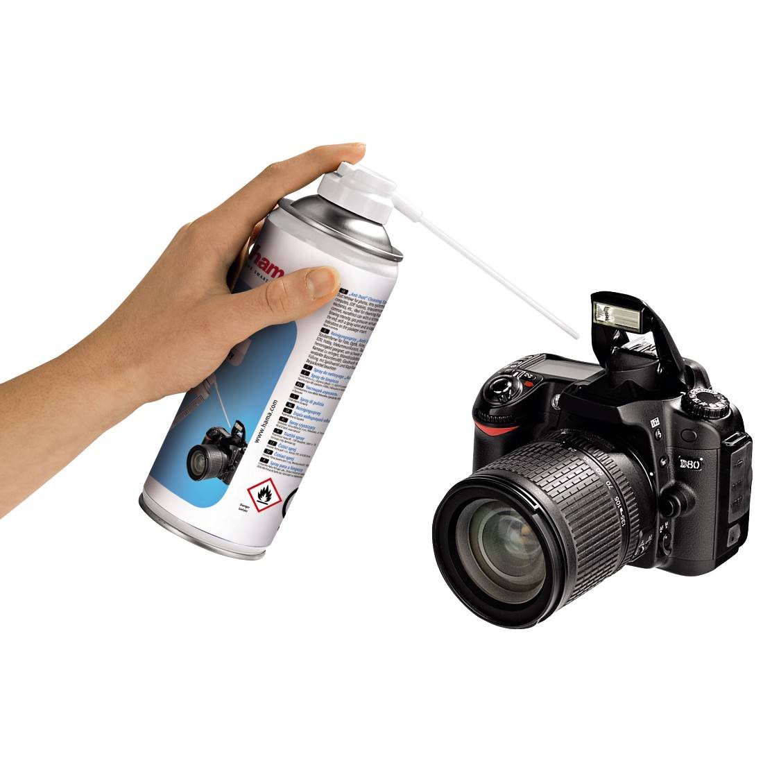 Eine Hand hält eine Druckluftdose und sprüht sie auf eine Digitalkamera mit ausgefahrenem Objektiv.