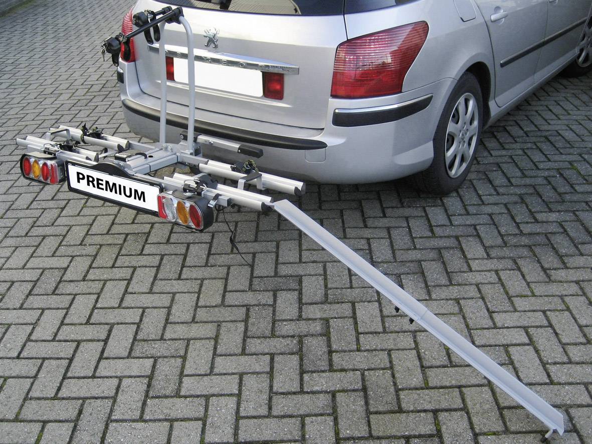Silbernes Auto mit installiertem Fahrradträger, auf dem Modell 'PREMIUM' steht. Träger ist bereit zur Aufnahme von Fahrrädern.