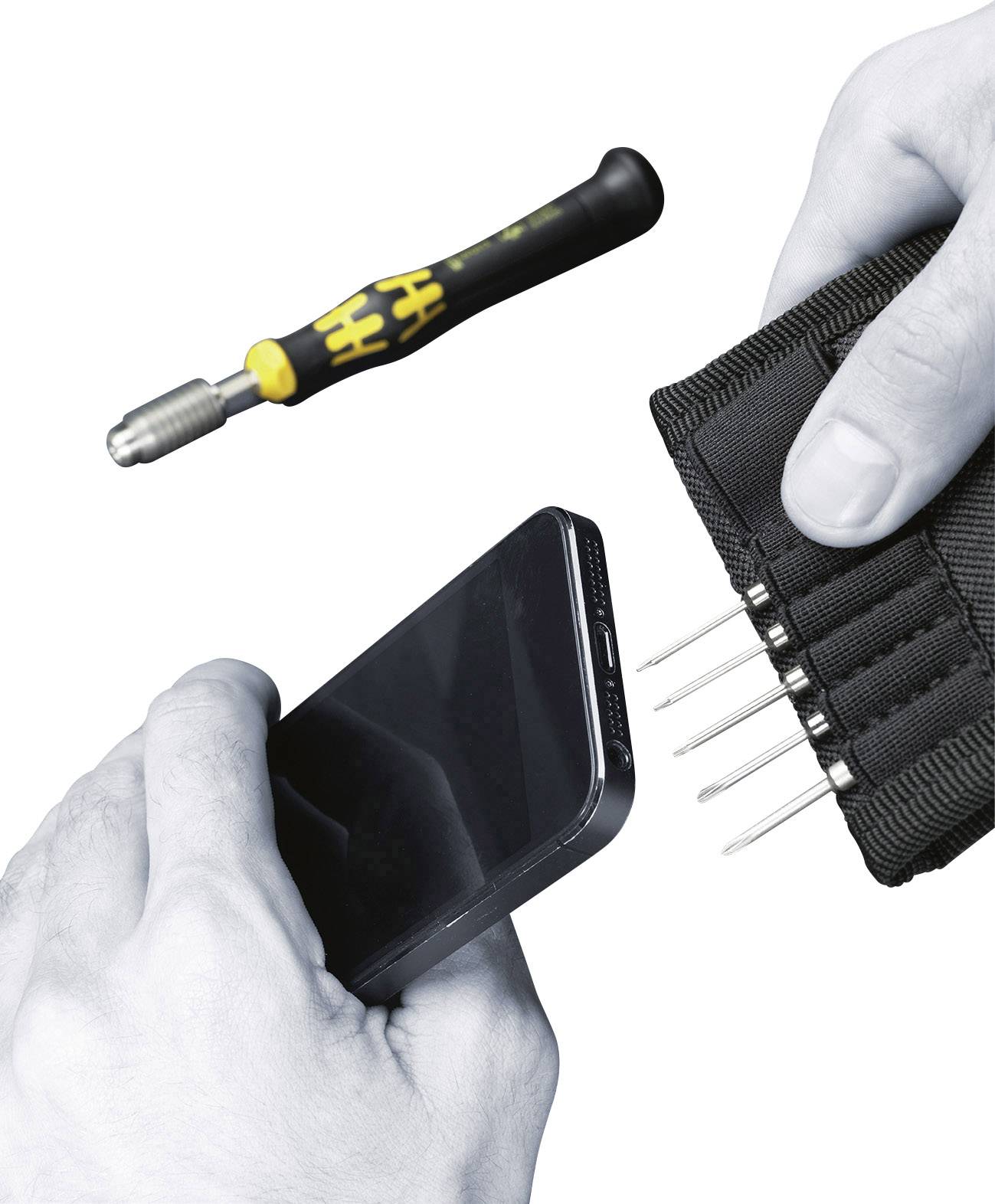 Eine Person hält ein Smartphone und ein schwarzes Etui mit mehreren Schraubendreherbits. Ein Schraubendreher liegt daneben.