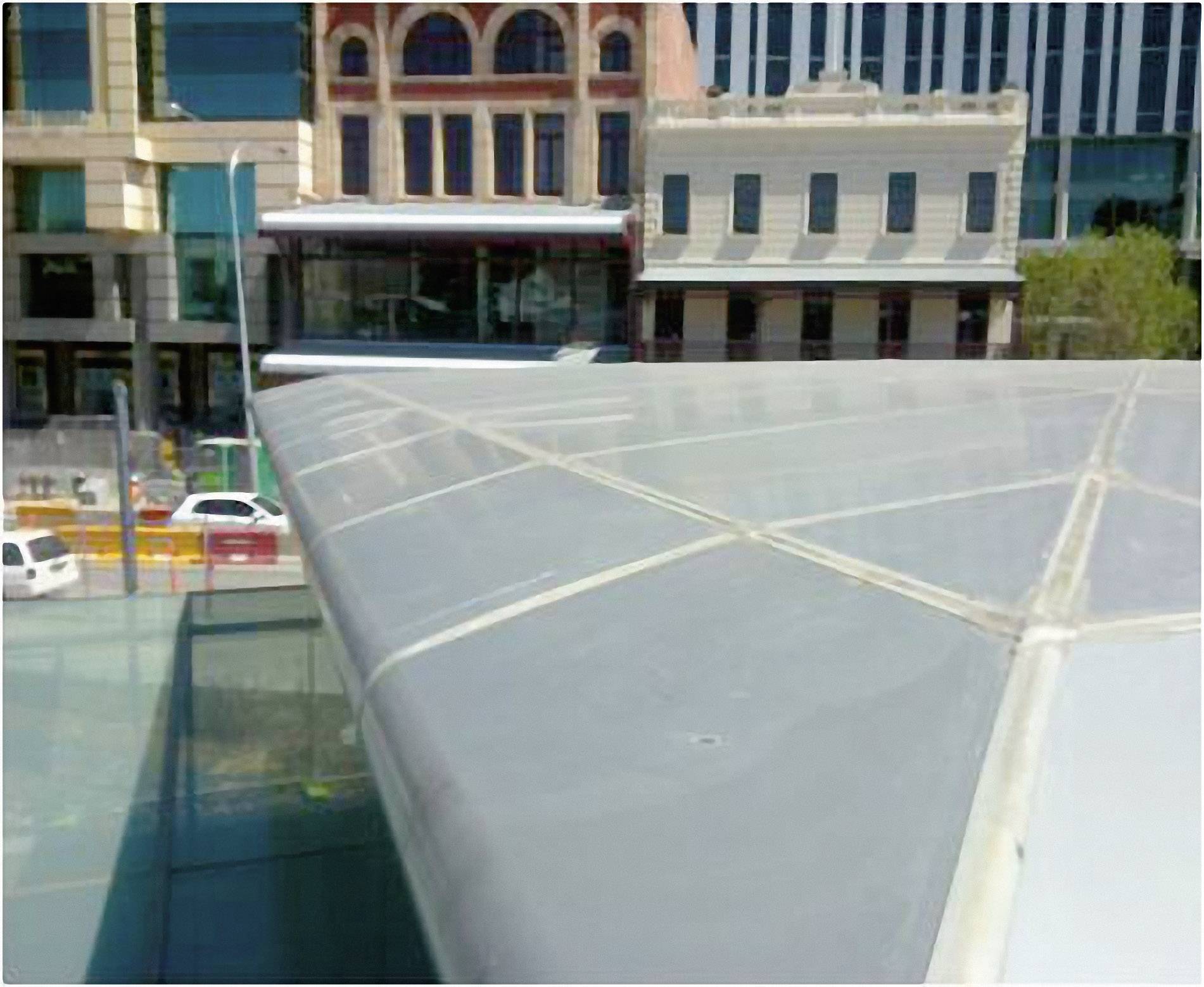 Blick auf moderne Glasarchitektur in urbaner Umgebung mit historischen Gebäuden im Hintergrund. Klare Linien und Kontraste sichtbar.