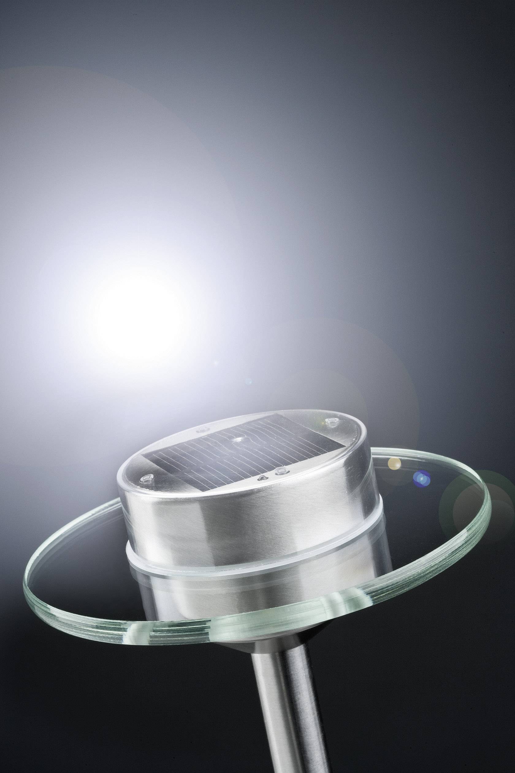 Eine Solarlampe mit rundem, modernem Design steht vor einem hellen Lichtschein. Ideal für umweltfreundliche Beleuchtung.