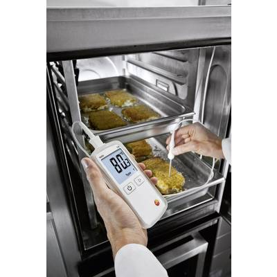 Eine Person misst mit einem digitalen Thermometer die Kerntemperatur von panierten Schnitzeln in einem Ofen. Temperatur zeigt 80,3°C.
