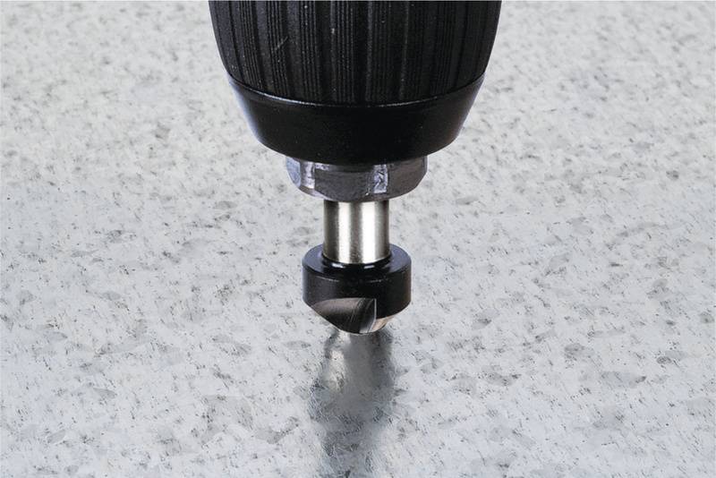 Ein Bohrer in Nahaufnahme, der in eine graue Steinoberfläche gebohrt wird. Der Bohrer erzeugt Staub und zeigt ein Loch im Entstehen.