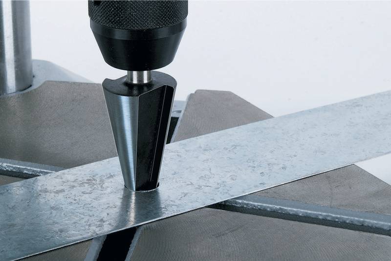 Metallbohrer beim Setzen einer Senkung auf einem Metallstreifen auf einer Werkbank.