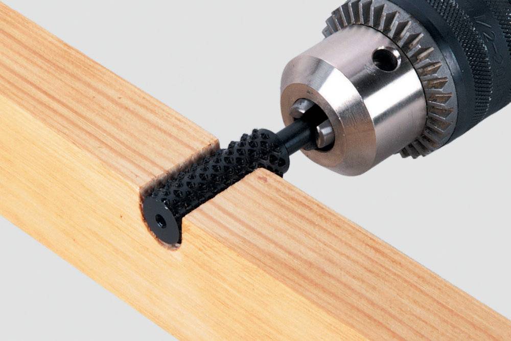 Eine Bohrmaschine bearbeitet Holz mit einem rotierenden Schleifkopf, um eine runde Vertiefung in die Oberfläche zu schleifen.