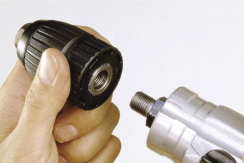 Eine Hand hält ein Werkzeugbohrfutter neben einem Bohrer. Das Bohrfutter wird offensichtlich entfernt oder montiert.