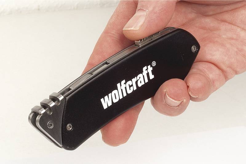 'Hand hält ein schwarzes Werkzeug mit der Aufschrift "wolfcraft".'