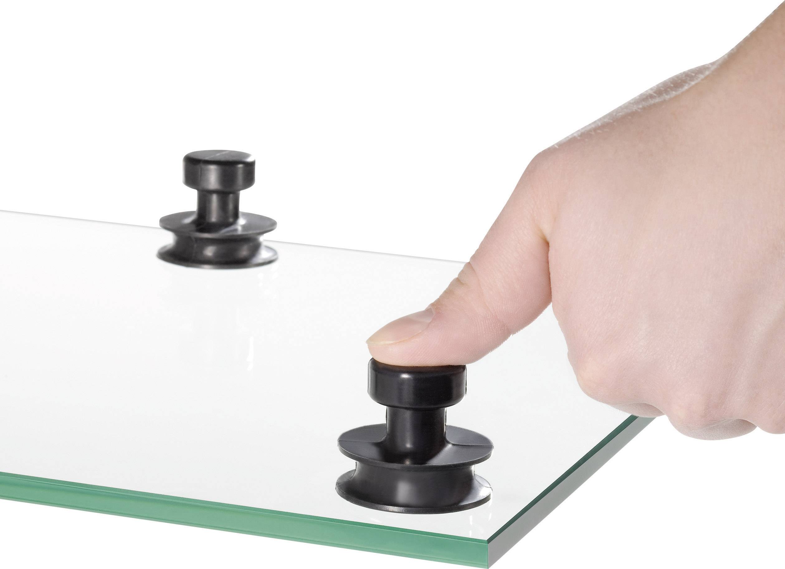 Hand drückt einen schwarzen Saugnapf auf eine Glasscheibe. Im Hintergrund ist ein weiterer Saugnapf zu sehen.