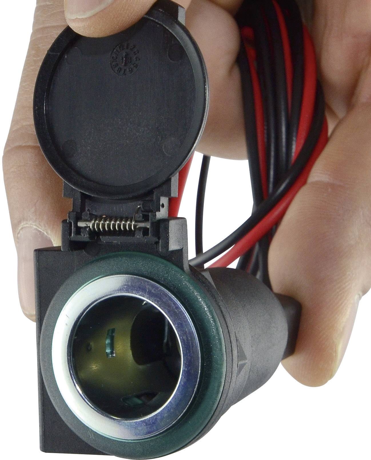 Eine Person hält eine schwarze Steckdose mit Abdeckung und roten sowie schwarzen Kabeln, bereit zur Installation.