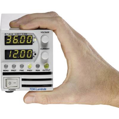 Hand hält ein elektronisches Gerät mit digitaler Anzeige. Oben steht '36,00' Volt, unten '12,00' Ampere. Markenname 'TDK-Lambda' sichtbar.