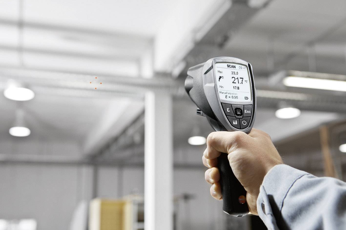 Infrarot-Messgerät in einer Industriehalle, das Thermometer zeigt mehrere Messdaten an.