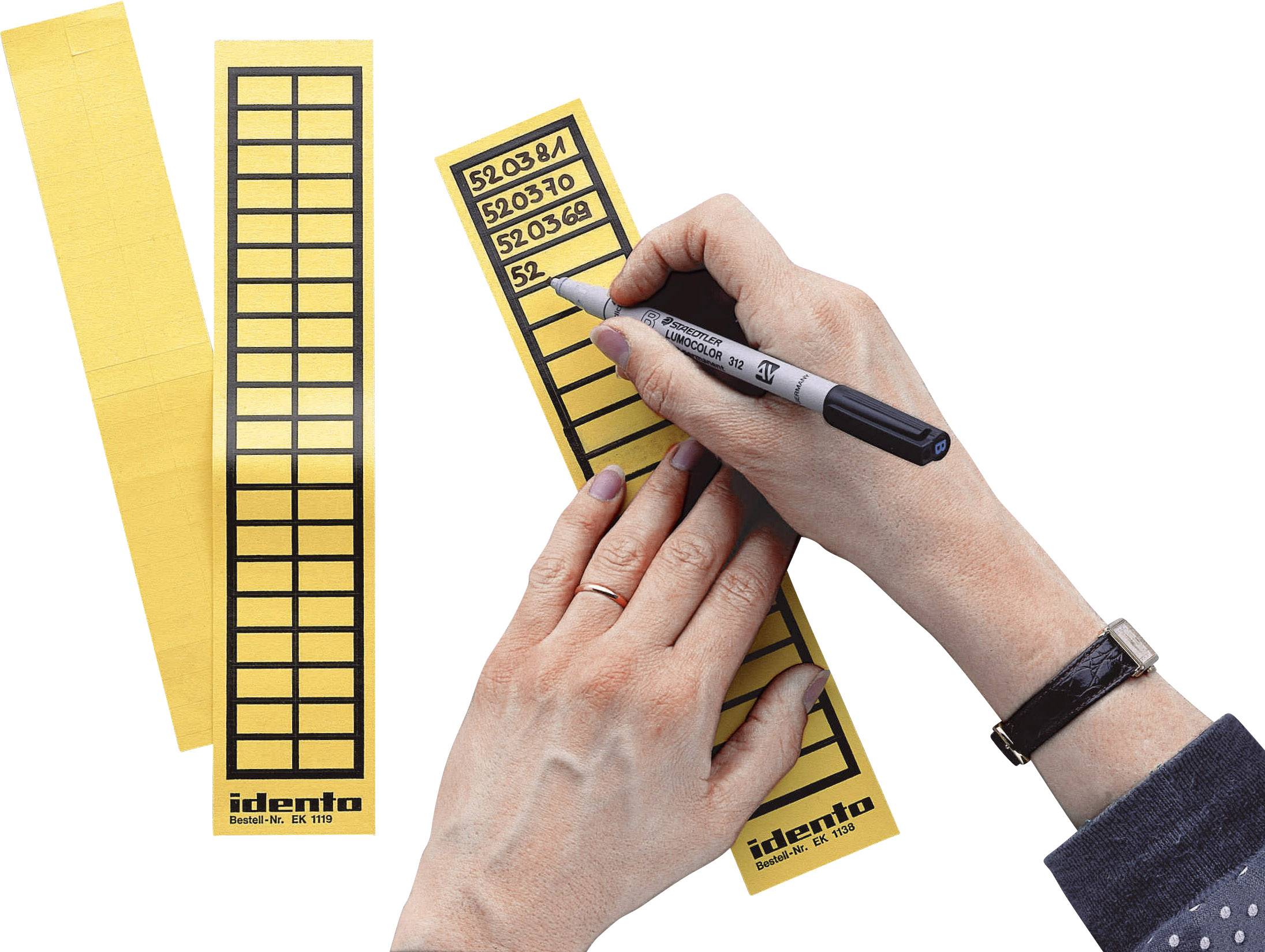 Eine Person beschriftet gelbe Etikettenstreifen mit regelmäßigen rechteckigen Feldern. Darunter steht 'identa'.