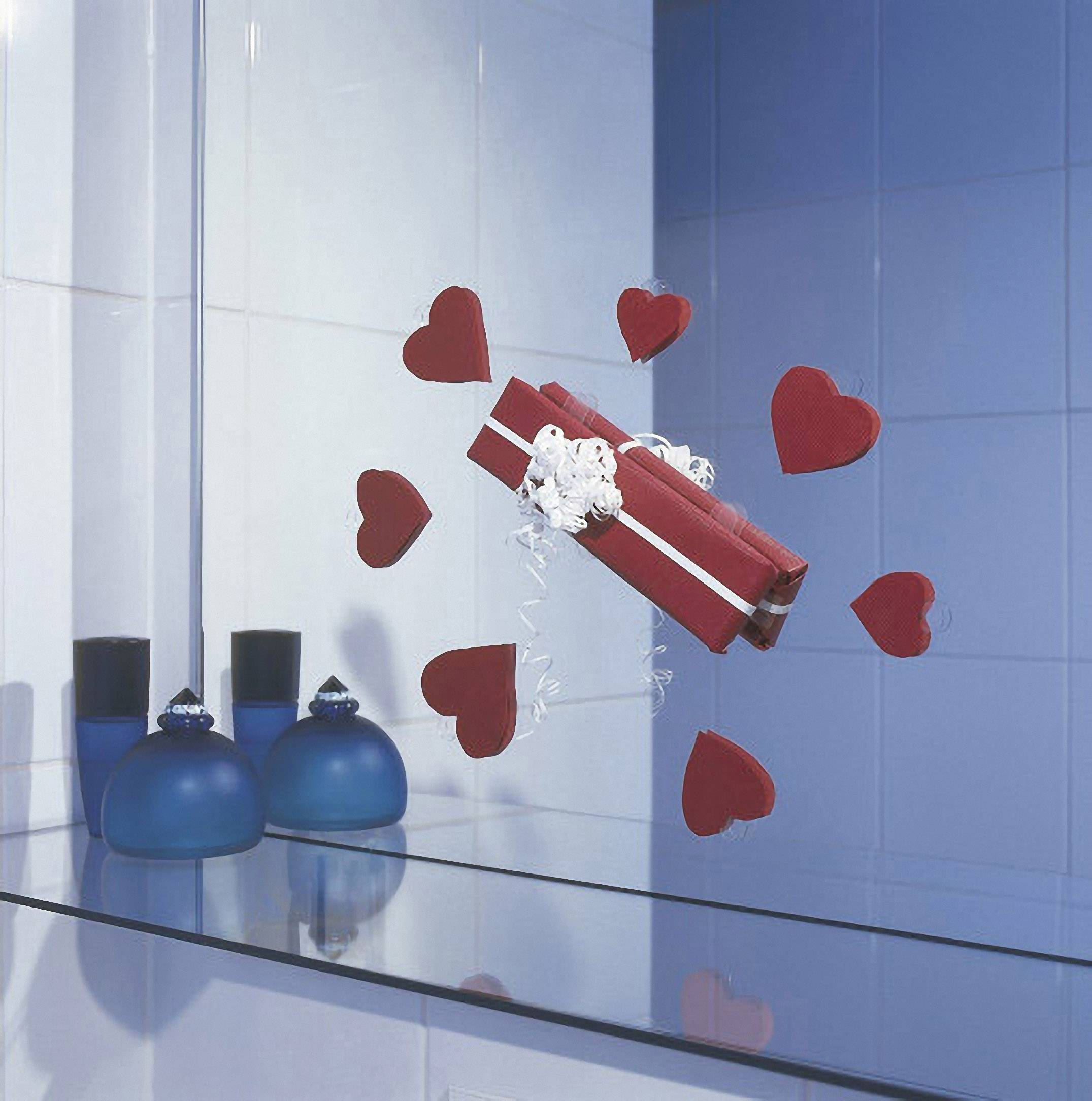 Rotes Geschenk mit weißen Schleifen, umgeben von Herzformen, schwebt über einer blauen Glasoberfläche in einem Bad mit blauen Fliesen.