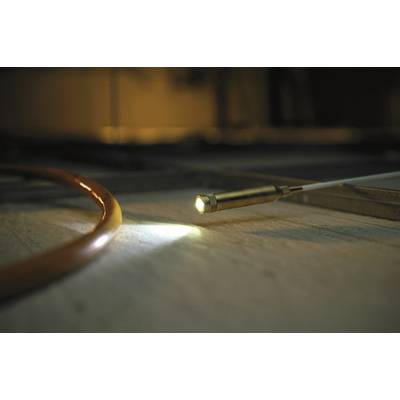 Ein Glasfaserlichtleiter leuchtet auf einen Boden. Neben ihm ist ein rotes Kabel zu sehen. Die Szene ist schwach beleuchtet.