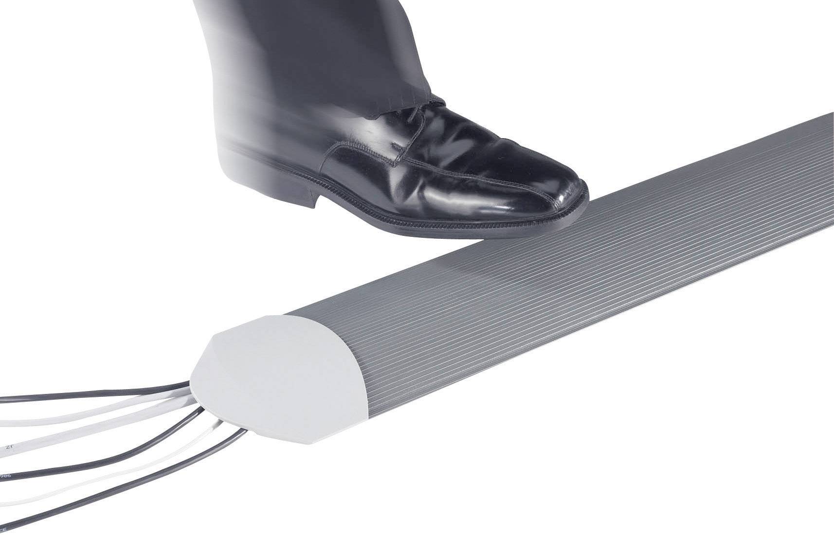 Ein Schuh tritt auf eine graue, kabelgebundene Fußmatte, die möglicherweise ein Signal oder eine Aktion auslöst.