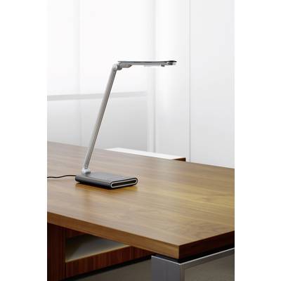 Eine moderne, schlanke Tischlampe steht eingeschaltet auf einem Holztisch vor einem neutralen Hintergrund.