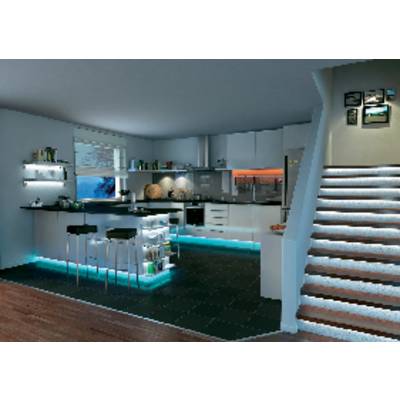 Moderne Küche mit Insel, Barhockern und subtiler Beleuchtung. Eine Treppe führt nach oben. Regalfläche mit Büchern und Dekoration.