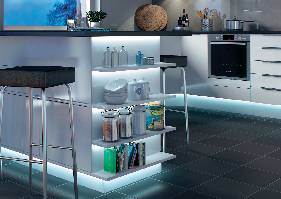 Moderne Küche mit weißer Theke und Barhockern, Regalen mit Kochbüchern und Geschirr, eingebautem Backofen und Deko-Elementen.