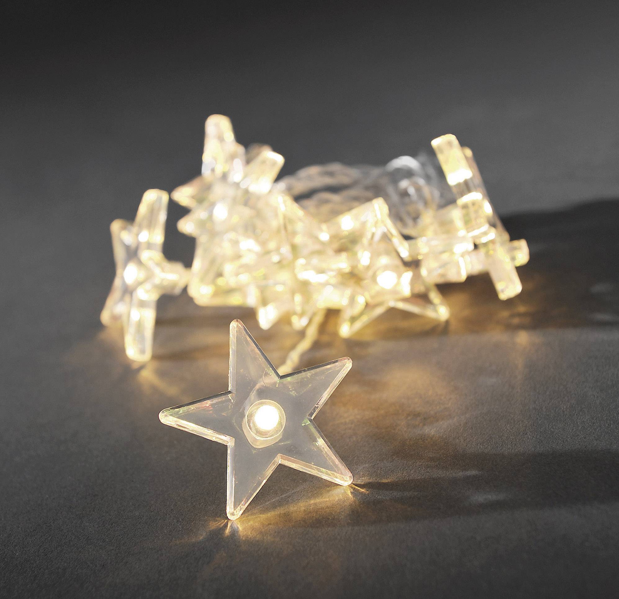 Sternförmige Lichterketten leuchten auf dunklem Hintergrund. Eine einzelne Lampe liegt im Vordergrund und ist besonders hell.