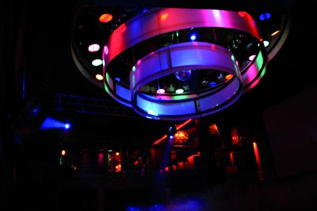 Bunte Lichter leuchten an der Decke eines dunklen Clubs, schaffen eine lebendige und dynamische Atmosphäre mit einer Diskokugel.
