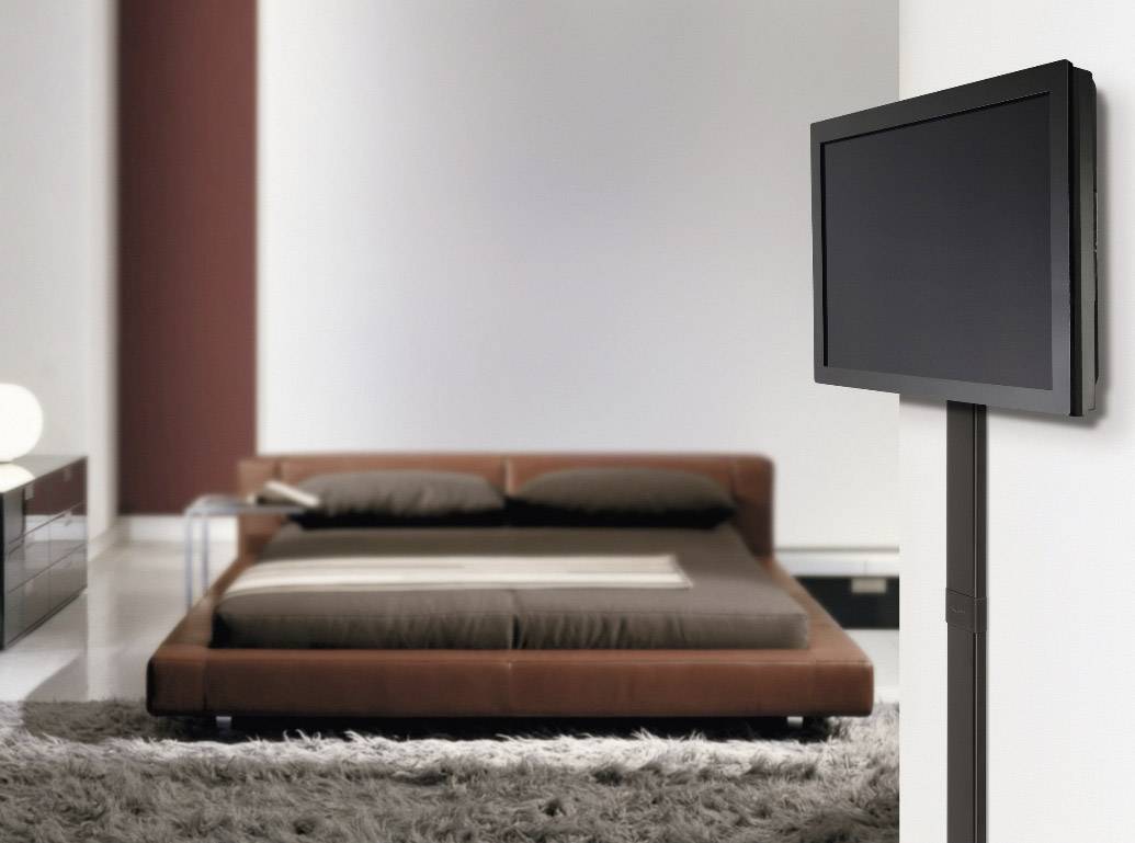 Ein modernes Schlafzimmer mit einem braunen Bett, einem flauschigen Teppich und einem Flachbildfernseher an der Wand.