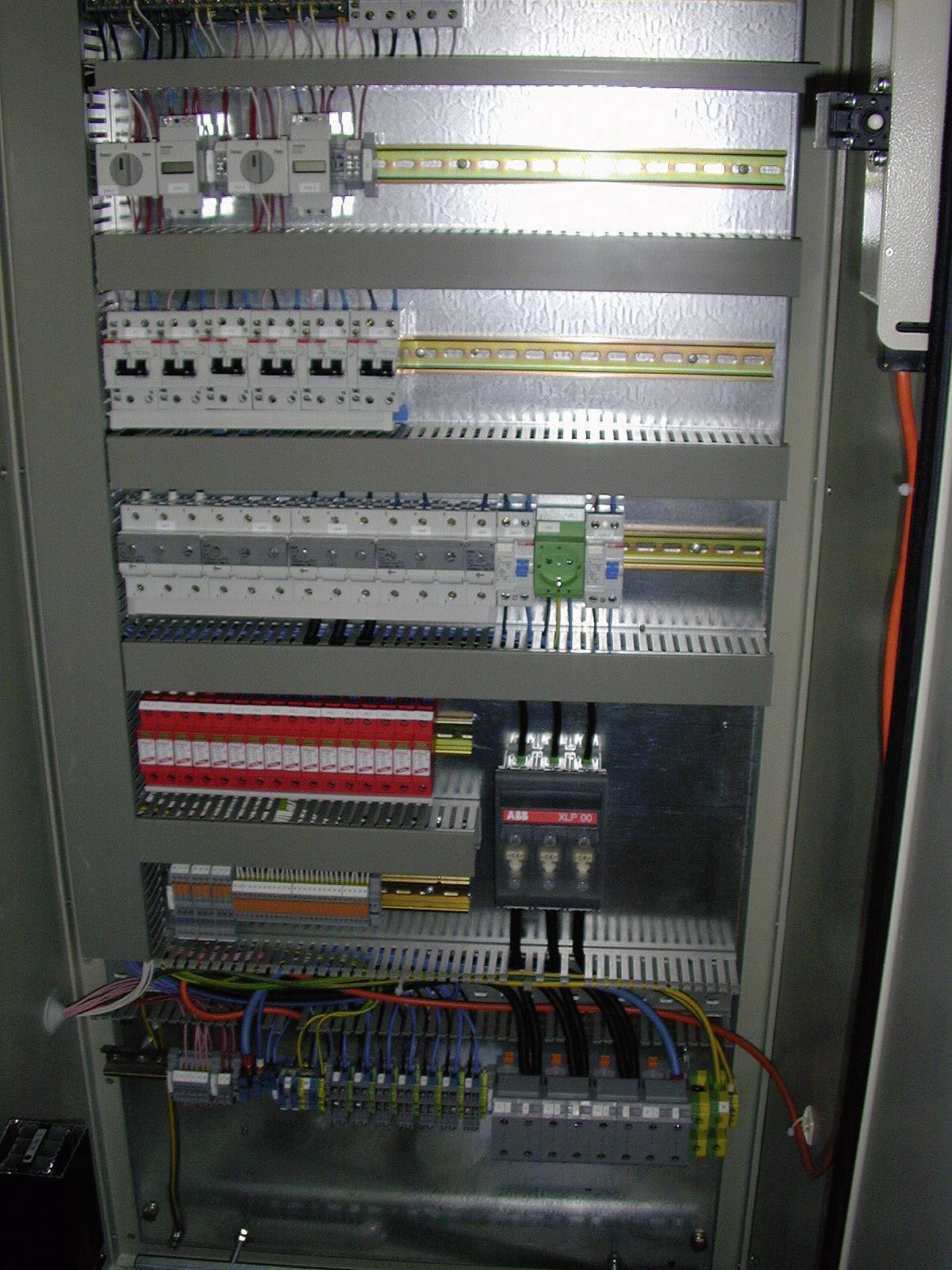 Ein geöffneter Schaltschrank mit verschiedenen elektrischen Komponenten und Drähten, die für Steuerungs- und Verteilungszwecke verwendet werden.