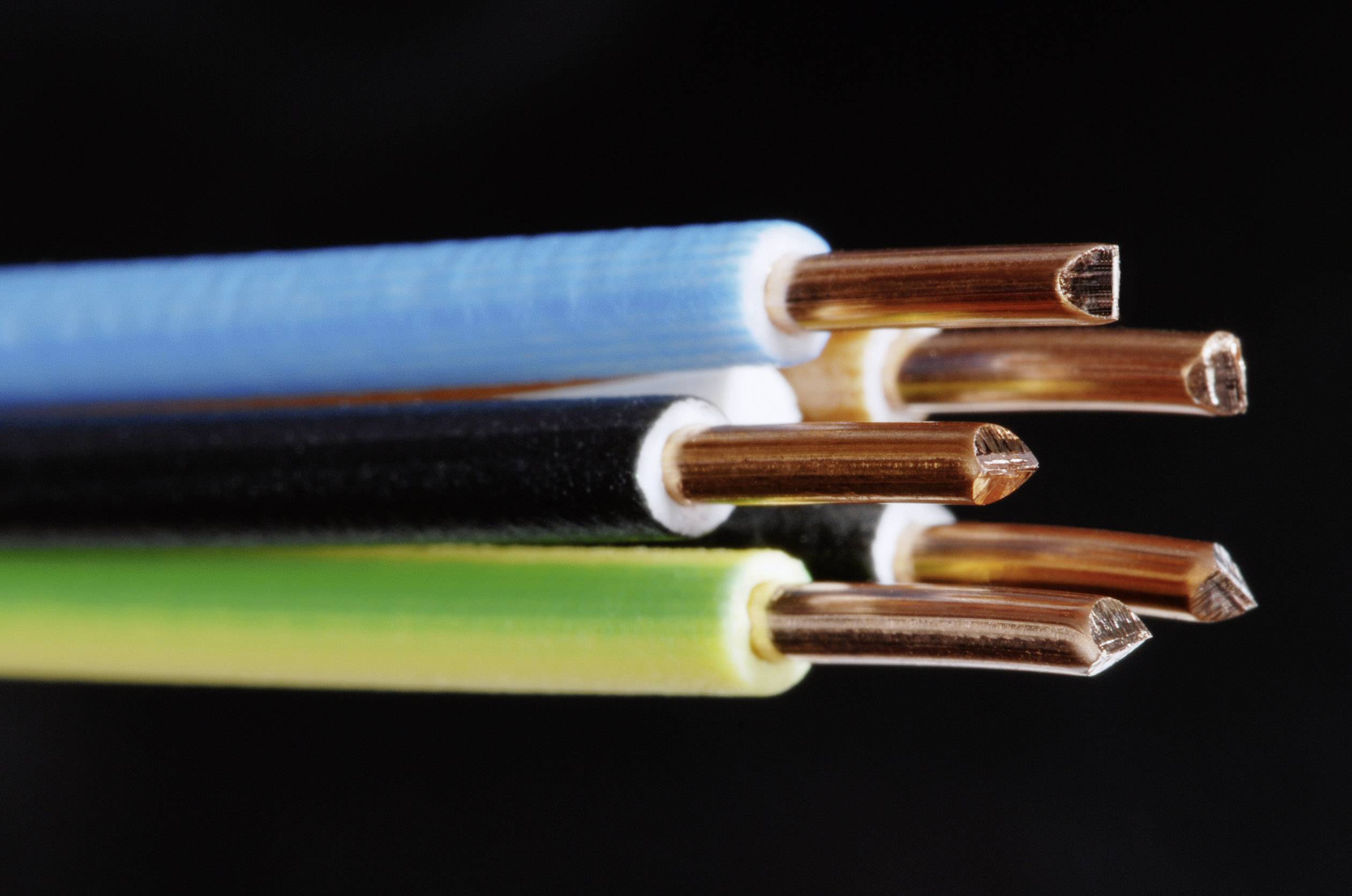 Mehrfarbige elektrische Kabel mit Kupferdrähten ragen heraus; Nahaufnahme vor schwarzem Hintergrund.