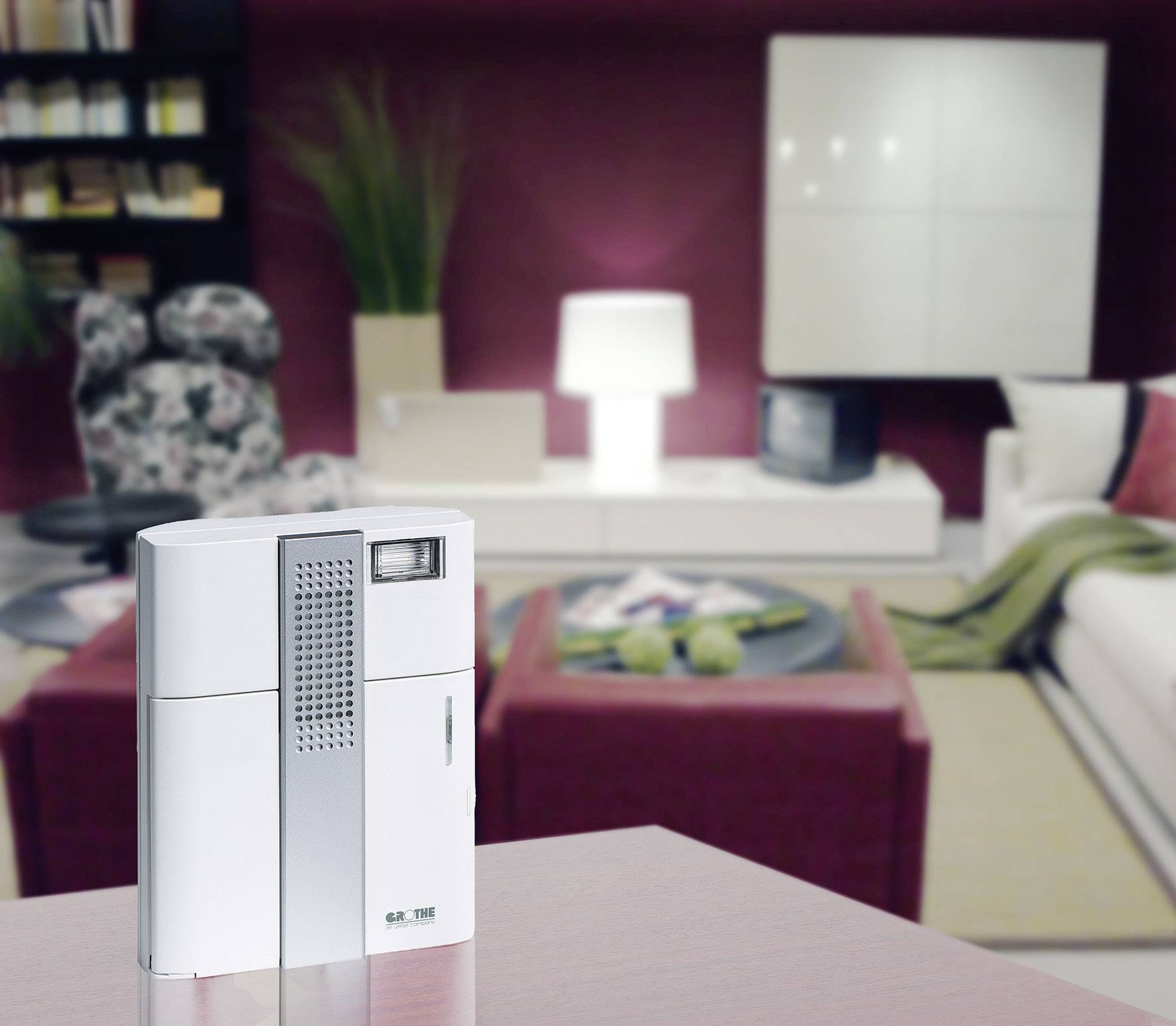 Ein weißer Luftreiniger steht auf einem Tisch in einem modern eingerichteten Wohnzimmer. Im Hintergrund sind Möbel und Dekorationen zu erkennen.