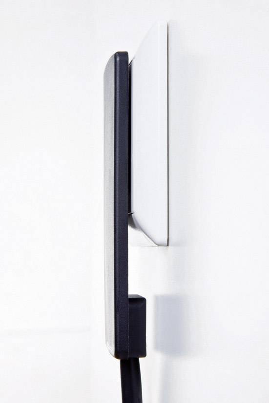Ein modernes, flaches Ladegerät ist in eine weiße Wandsteckdose eingesteckt, seitliche Ansicht mit sichtbarem schwarzem Kabel.