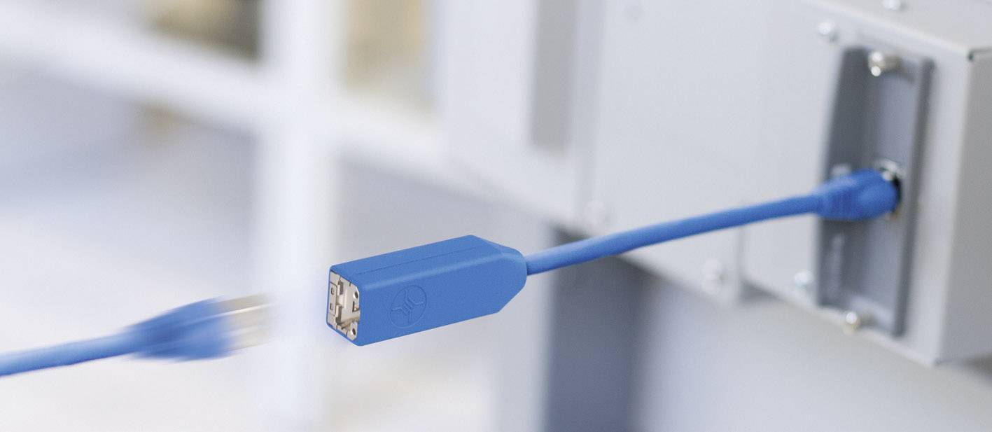 Blaues Netzwerkkabel wird in einen Port gesteckt, zeigt einen Verbindungsaufbau in einem technischen Umfeld.