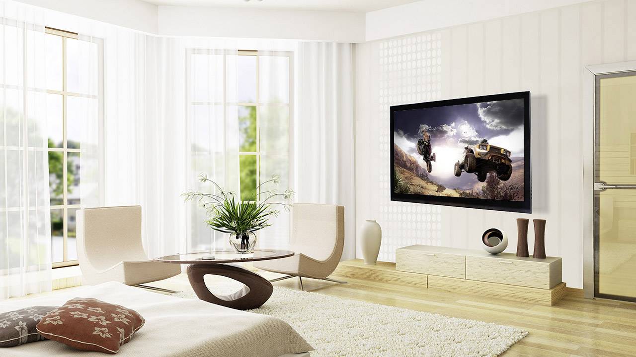 Großes, modernes Wohnzimmer mit hellem Holzboden. An der Wand hängt ein Flachbildfernseher, der eine Landschaftsszene mit Fahrzeugen zeigt.