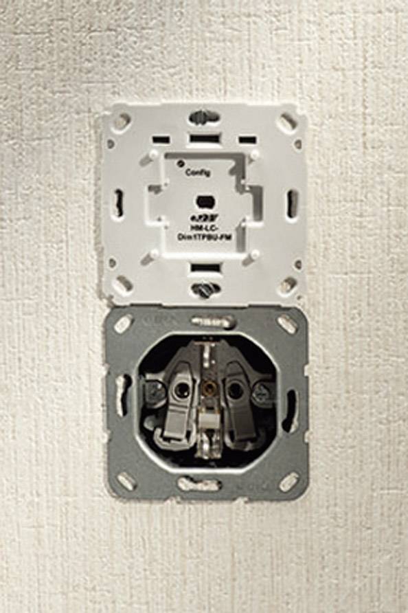 Eine offene Wandsteckdose ohne Abdeckung zeigt die Metallkontakte und interne Verkabelung vor einer beigen Wand.