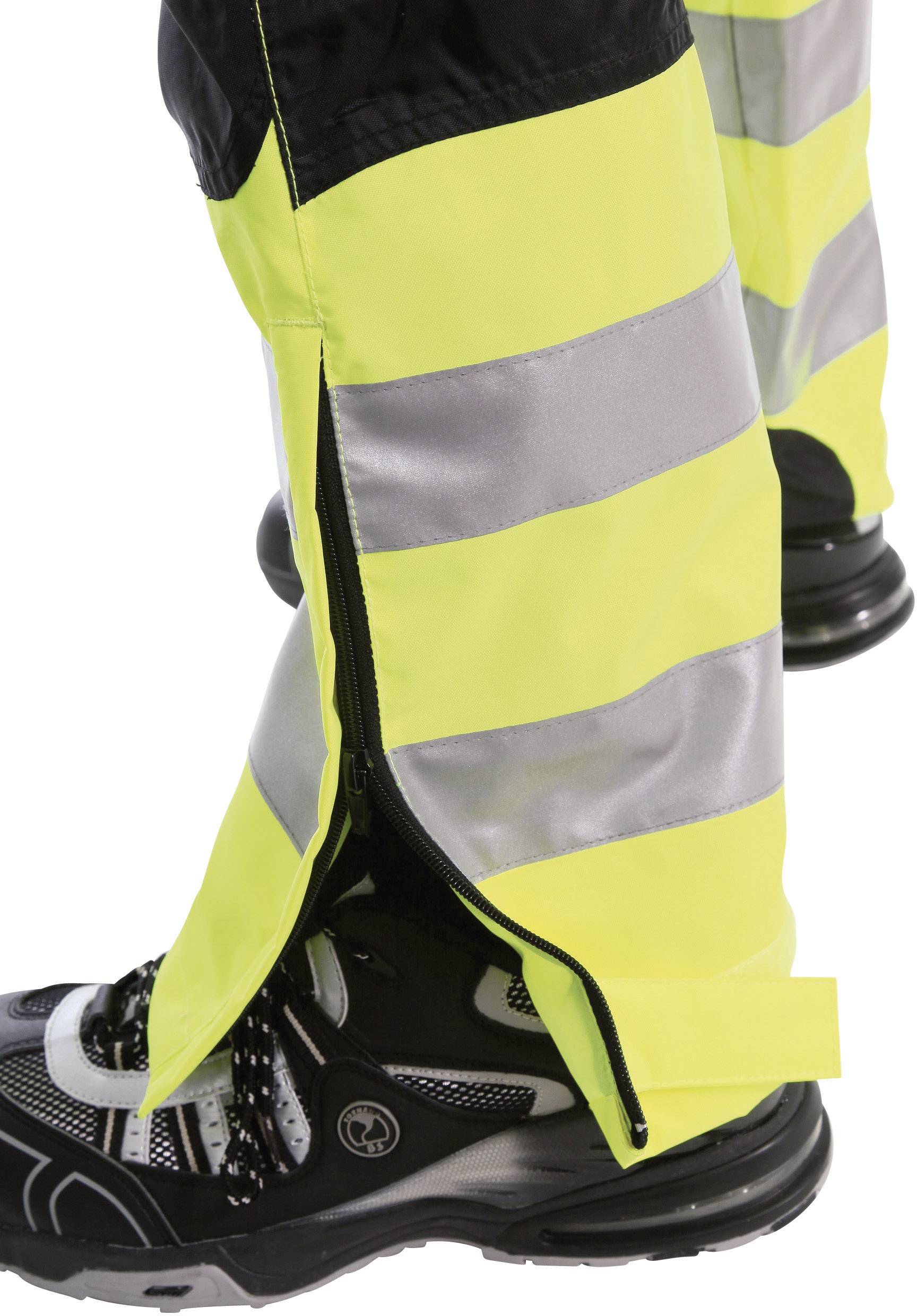 Person in reflektierender Sicherheitskleidung und schwarzen Schuhen. Die Kleidung hat gelbe und silberne Streifen. Profilansicht.