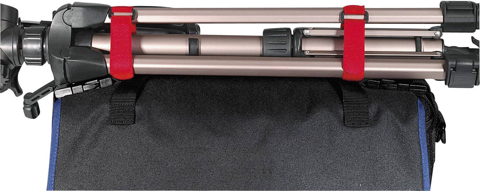 Ein zusammengeklappter Stativ wird mit roten Gürteln an einer schwarzen Tasche befestigt.