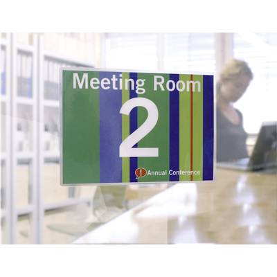 Ein Schild mit der Aufschrift 'Meeting Room 2' und 'Annual Conference' auf gestreiftem Hintergrund. Im Hintergrund ist eine unscharfe Person.