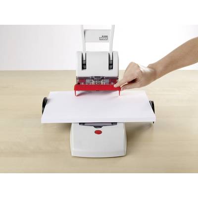 Eine Hand benutzt eine manuelle Maschine, um ein Blatt Papier auf einem Tisch zu perforieren.
