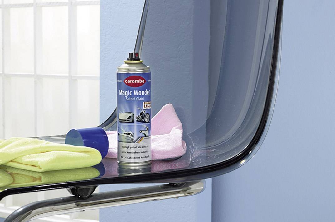 Eine Sprühdose 'Magic Wonder', umgeben von verschiedenfarbigen Tüchern, steht auf einem transparenten Stuhl vor einer blauen Wand.